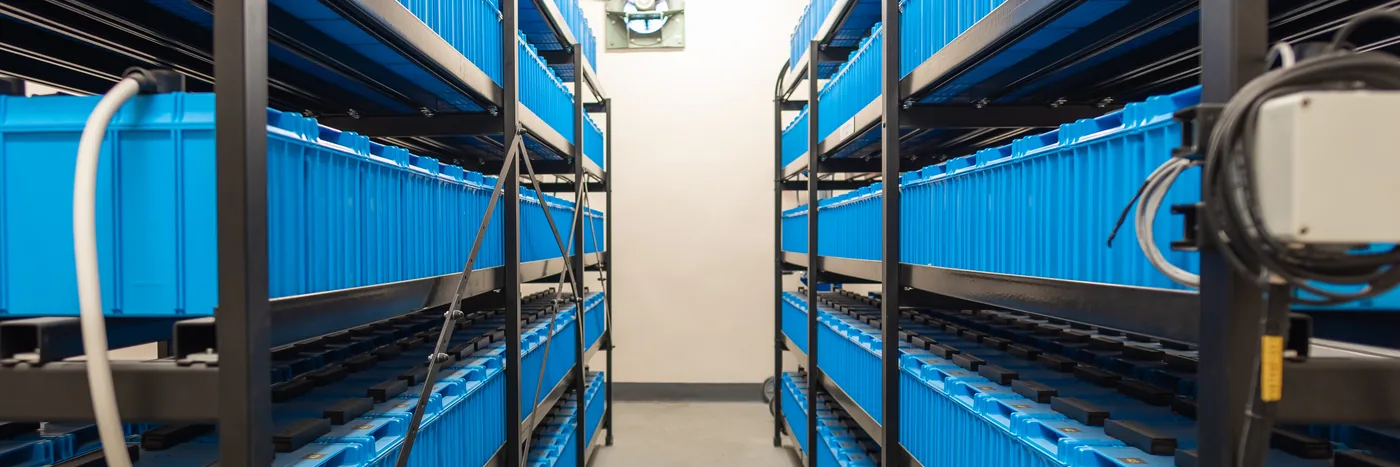 Rows of blue industrial battery cells racked floor to ceiling in a backup power room.